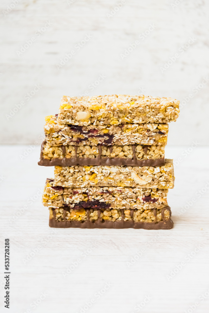 A pile of of various homemade granola bars with nuts, seeds, dark chocolate, honey and berries over a wooden background.