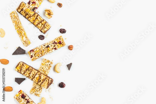 Obraz na płótnie Top view of various homemade granola bars with nuts, seeds, dark chocolate, honey and berries over a white background. Copy space. w salonie