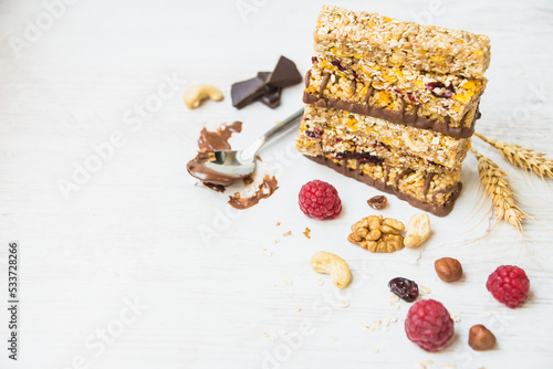 A pile of various homemade granola bars with nuts, seeds, dark chocolate, honey and berries over a white wooden background. Copy space.