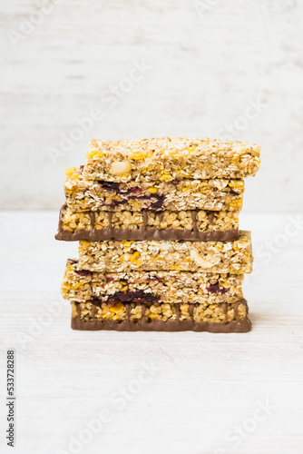 Obraz na płótnie A pile of of various homemade granola bars with nuts, seeds, dark chocolate, honey and berries over a wooden background. w salonie