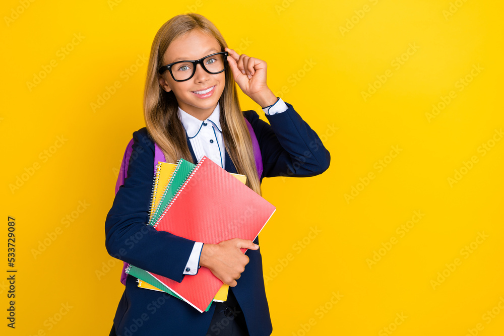 Photo of cheerful girl hand touch eyewear stylish clothes hold notebook folders want school empty space isolated on yellow color background Photo of cheerful girl hand touch eyewear stylish clothes hold notebook folders want school empty space isolated on yellow color background