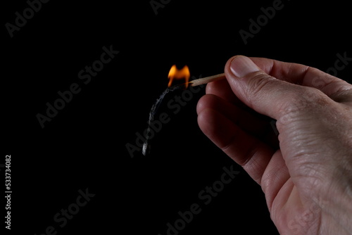 Match stick ignited burning bright big fire flame in hand isolated on black