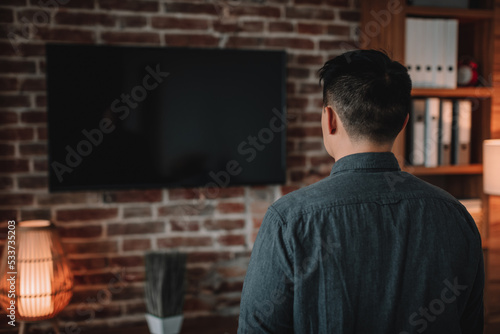Mature korean man watching tv with empty screen, enjoy show in home office interior, back
