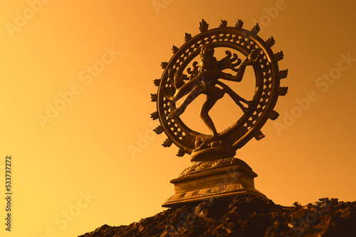 Dancing bronze Shiva on a yellow-orange background. Space for text.
