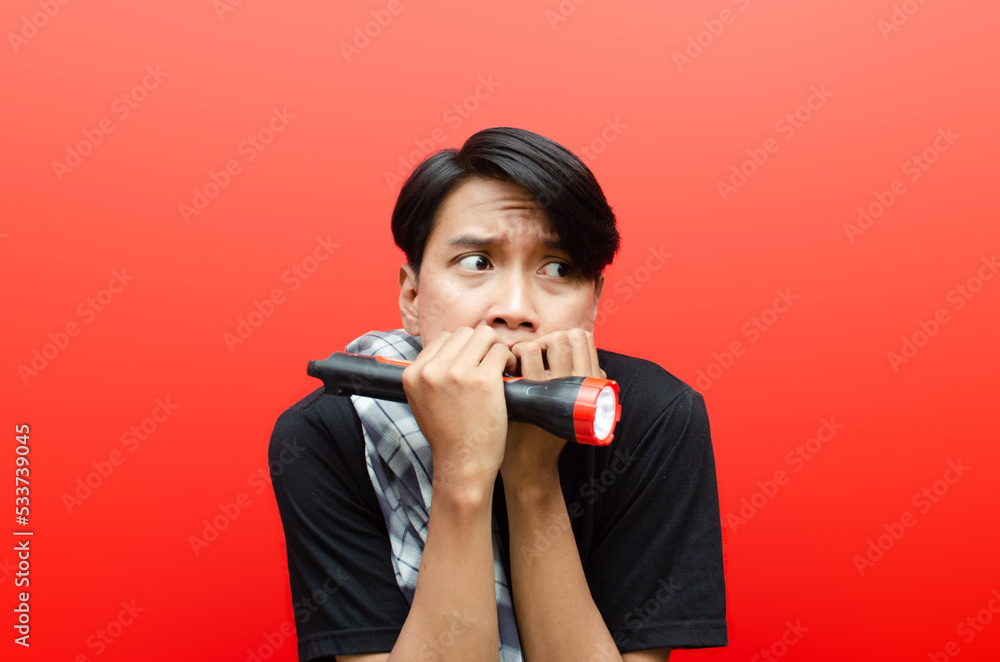 Asian man is terrified covering mouth and trembling. asian man scared and making frightened gesture. horror concept. man with sarong and flashlight doing patrol or ronda. Asian man is terrified covering mouth and trembling. asian man scared and making frightened gesture. horror concept. man with sarong and flashlight doing patrol or ronda.