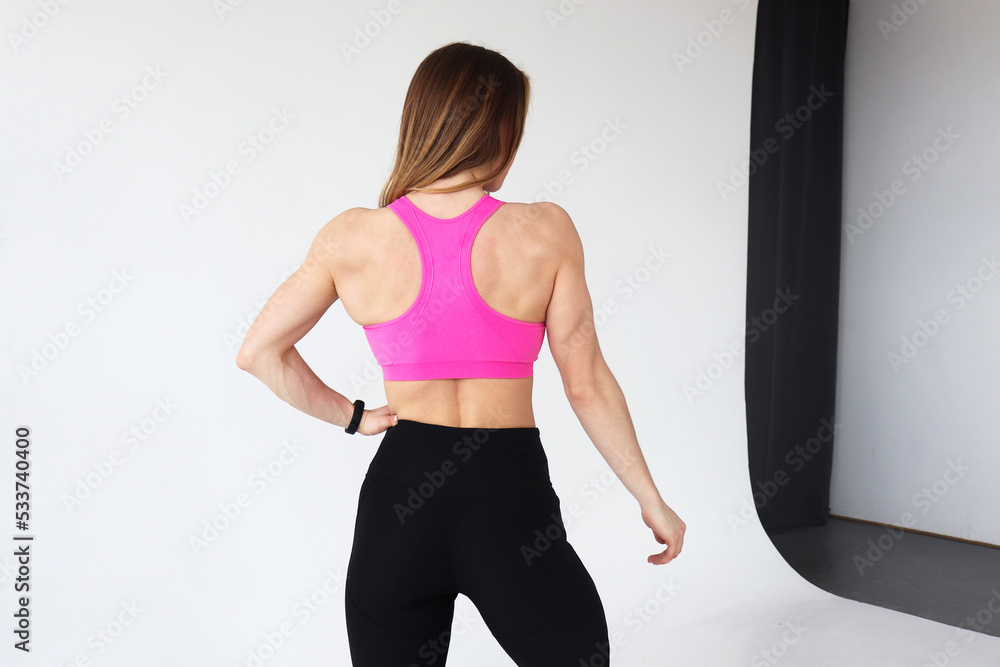 Muscular body of a young woman in sportswear, close up. Female back isolated on a white background.