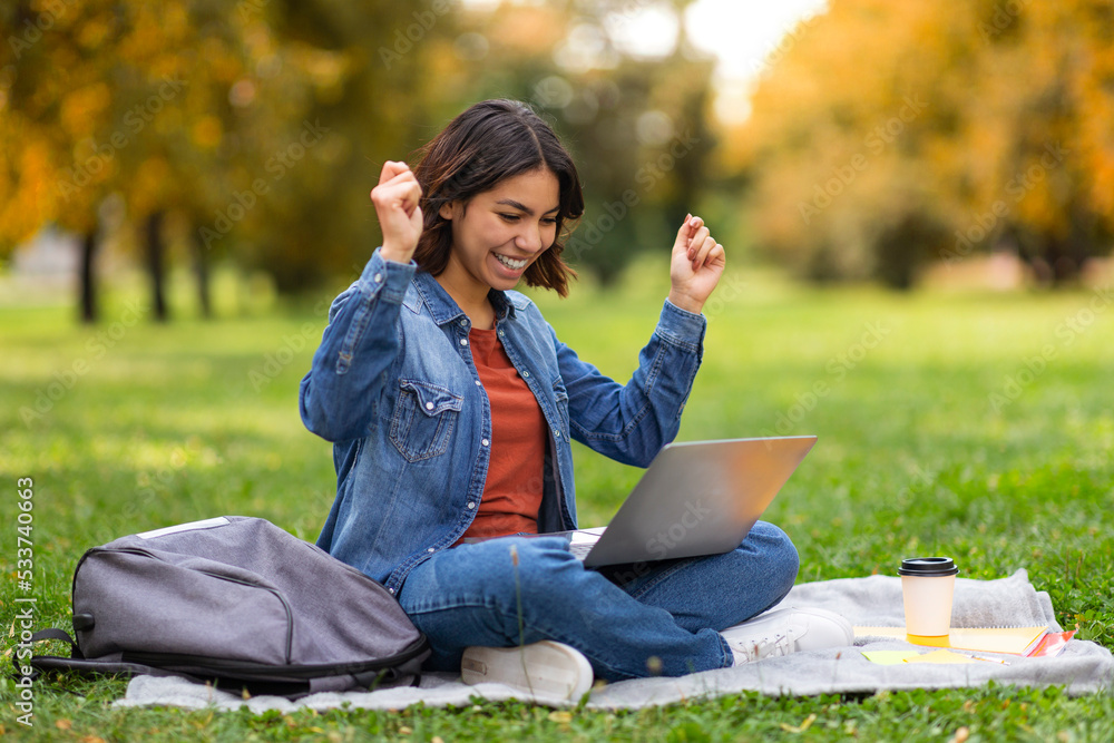 Good News. Joyful Arab Female Student Celebrating Success With Laptop Outdoors Good News. Joyful Arab Female Student Celebrating Success With Laptop Outdoors