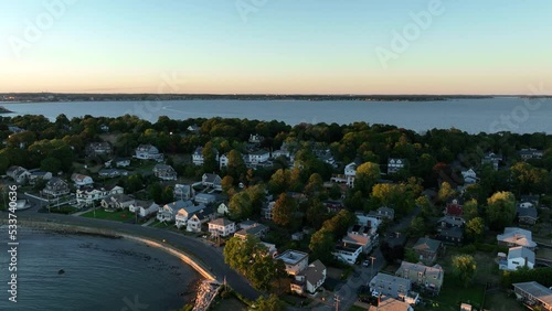 Aerial drone footage of Nahant, Massachusetts near Boston. Beautiful pink sky sunset on the Atlantic Ocean during summer. Waves on the rocky shoreline and Boston cityscape in the distance. photo