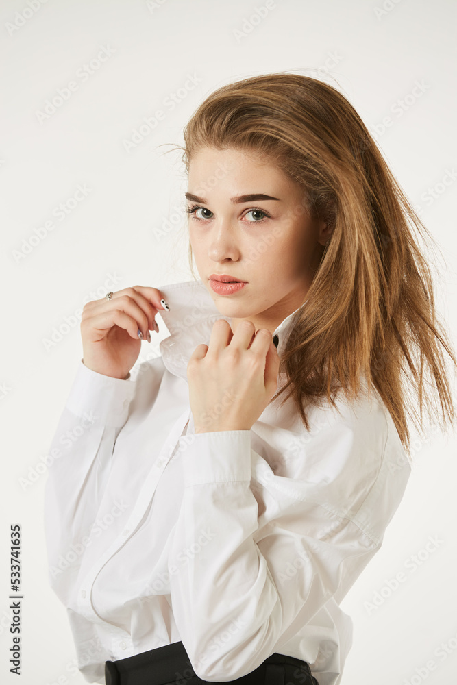 A girl in a white shirt stands on a white isolated background. A girl in a white shirt stands on a white isolated background.