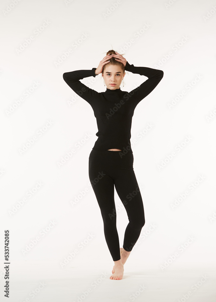 A girl in black clothes on a white isolated background performs dance and ballet poses and movements. A girl in black clothes on a white isolated background performs dance and ballet poses and movements.