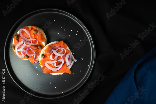 Bagel with cream cheese, red onion, capers, and salmon shot overhead photo