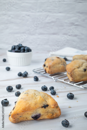 Freshly baked blueberry scones cooling on a rack on a marble countertop 