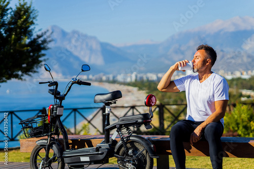 old-aged man good loking outdoors with eco scooter enjoying morning and drinking coffee