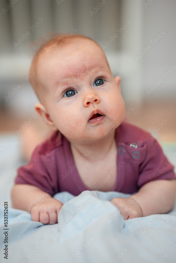 Close-up portrait of a cute Caucasian newborn baby. Charming funny baby baby looking into the camera. An authentic childhood and a candid lifestyle moment.