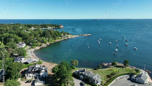 Aerial drone footage of Nahant, Massachusetts near Boston. Beautiful blue sky, green forest and waves crashing on the rocky shore of the Atlantic Ocean during summer.