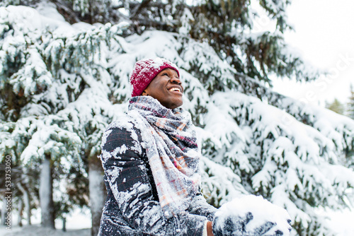 african american man in a snowy winter woodland with snowflakes falling from spruce and fir forest
