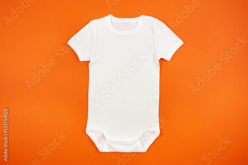 White baby girl or boy bodysuit mockup flat lay on orange background. Design onesie template, print presentation mock up. Top view.