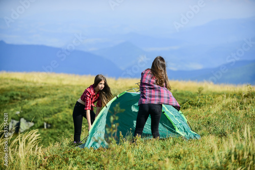 Feeling playful. friends spend free time together. family camping. reach destination place. two girls pitch tent. wanderlust discovery. hiking outdoor adventure. mountain tourism camp photo