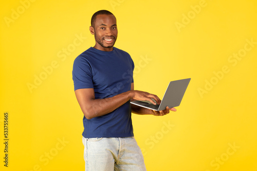 Obraz na plátně Happy Black Man Using Laptop Posing On Yellow Background