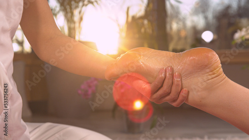 CLOSE UP: Sun shinning through massaging hands while performing reflexotherapy photo