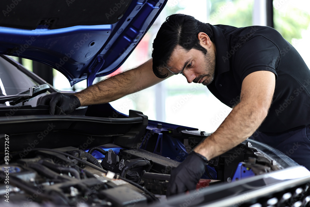 Professional mechanic working on the engine of the car in the garage. Car repair service. Professional mechanic working on the engine of the car in the garage. Car repair service.
