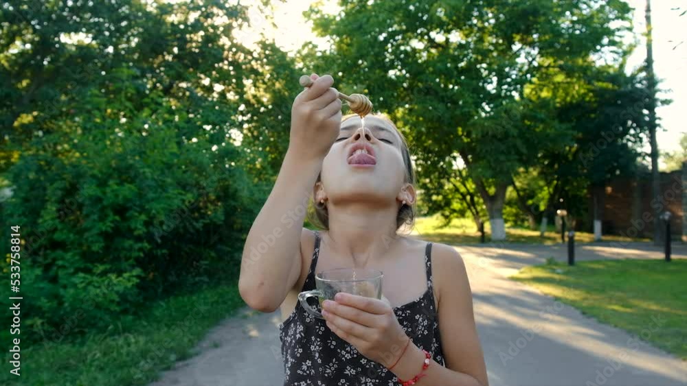 The child eats honey in the garden. Selective focus. The child eats honey in the garden. Selective focus.