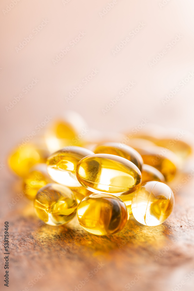 Fish oil capsules. Yellow omega 3 pills on wooden table. Fish oil capsules. Yellow omega 3 pills on wooden table.