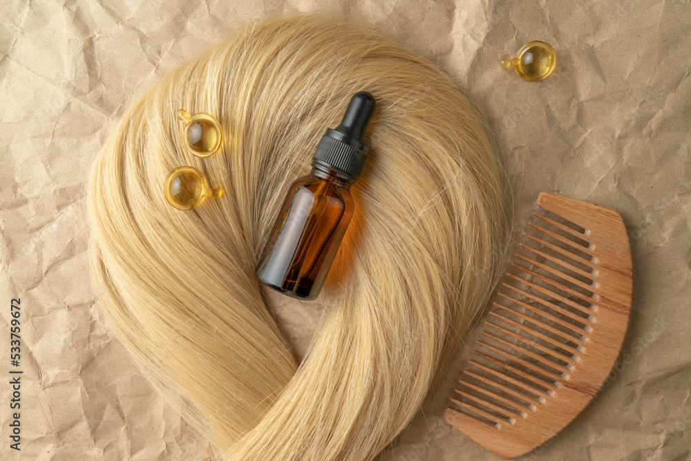 Fototapeta premium A hair treatment essential oil for smoothing hair lying on a strand of blond hair
