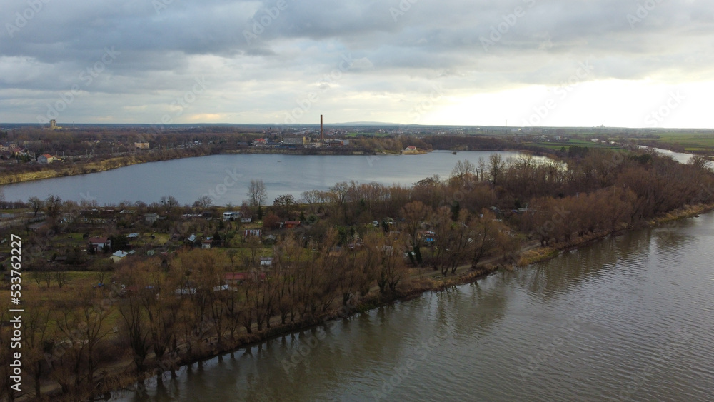 Top view of the river Odra and lake Bolko. Dry trees on the banks. In the background of the house. Poland, Opole