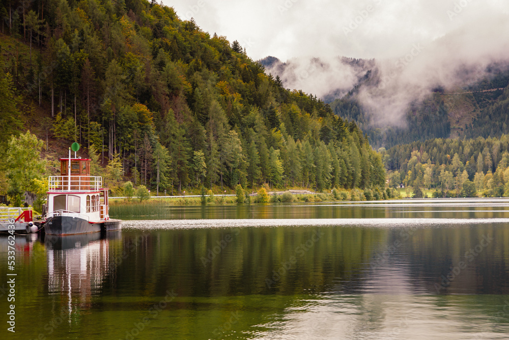 Fototapeta premium Erlaufsee mit einem Boot Wald und grünem Wasser Wolken nach dem Regen