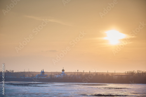 sunset over the Orthodox monastery. Russian city in the spring, ice on the river photo