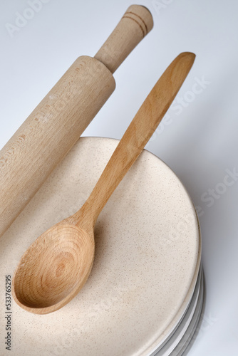 Plates, wooden spoon and rolling pin on a light background. Kitchenware. Cooking concept 