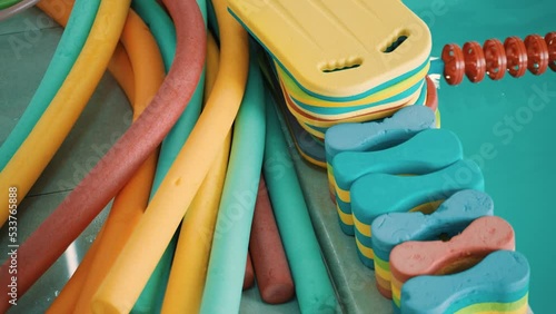 Items for swimming. Swimming boards, aqua noodles and buoys by the pool on tiles. Accessories for swimming. Tools for aerobics and swimming training. Swimming lessons.  photo