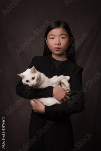 asian girl holding white cat in classic painterly studio portrait