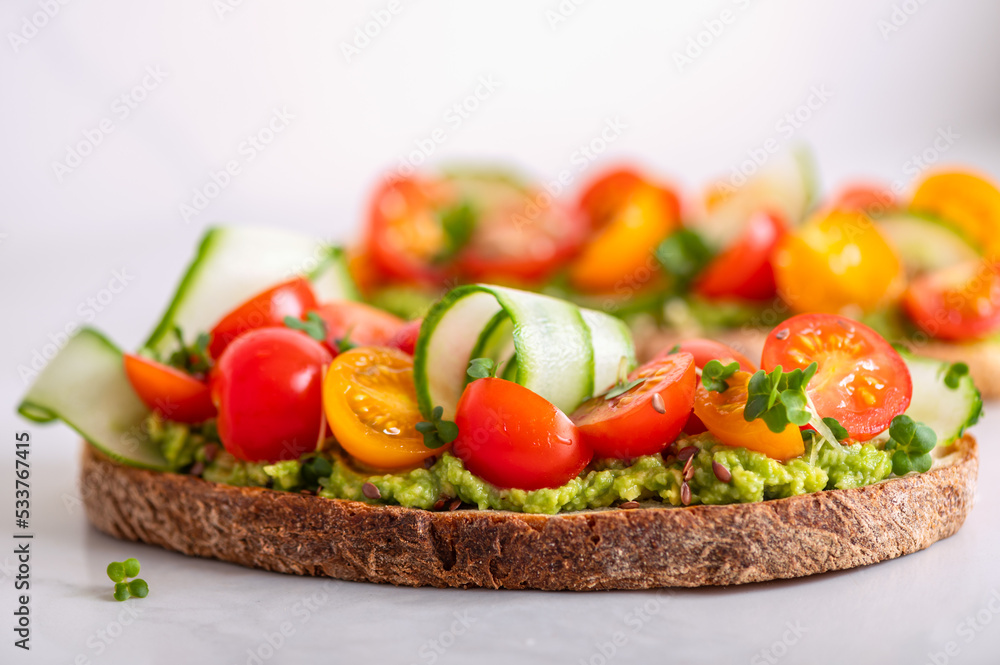 Tasty open sandwich from toasted sourdough bread with mashed avocado and fresh tomatoes