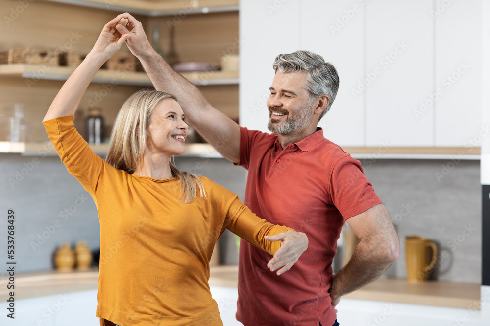 Fototapeta premium Loving middle aged couple dancing at kitchen