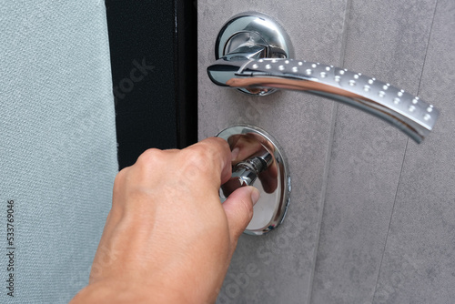 A hand locking the door with a door knob for security, protection from robbery and theift photo