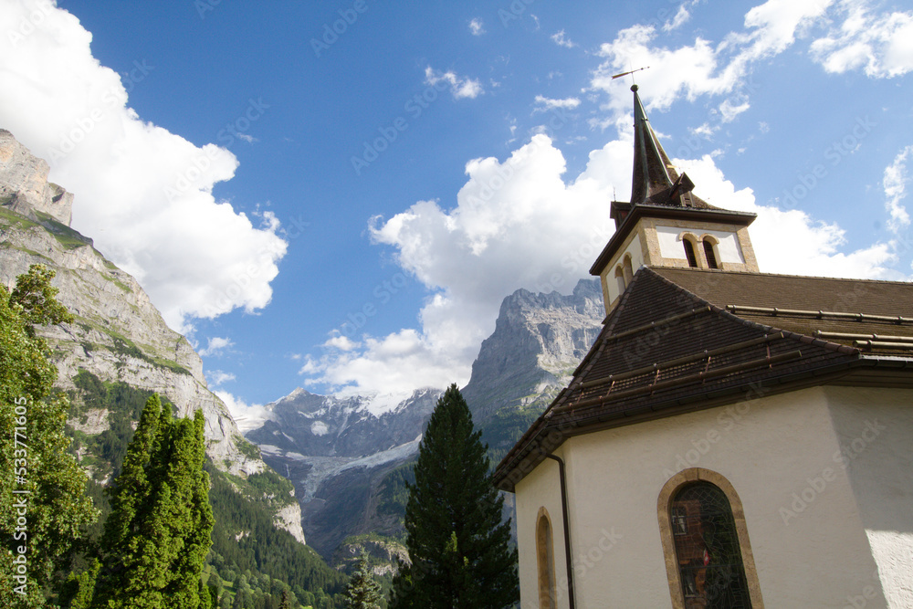Catholic church in alpine valley. Religious building surrounded by tall mountains in Switzerland