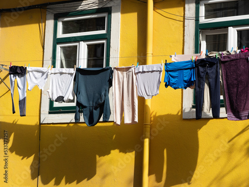 Lissabon - Stadtteil Mouraria: Wäsche zum Trocknen an gelber Hausfassade photo