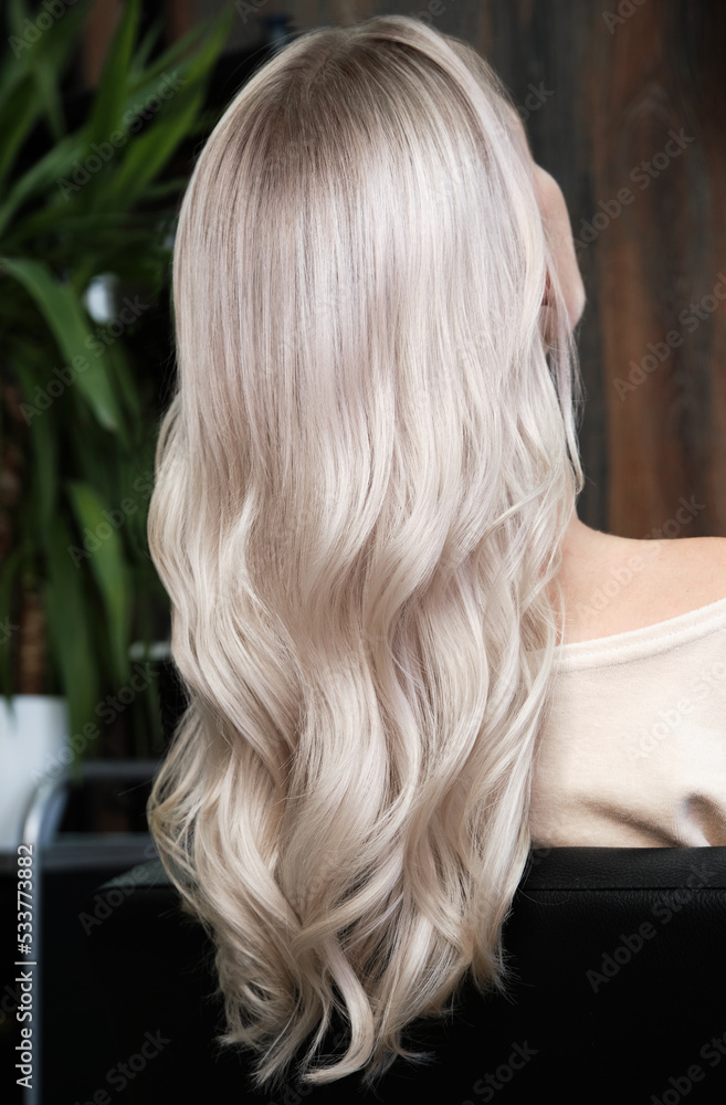 Naklejka premium Young woman in a hairdressing salon dyes her hair blond