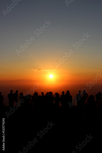 silhouette of people at sunset above the sea. Silhouette of people enjoying the orange sunset above the sea. 