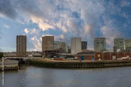 Antwerpen, Flanders, Belgium - July 10, 2022: Along Scheldt River. Line of 5 tall condominium towers along Battaviastraat at Kattendijk lock under blue sunrise cloudscape. Historic warehouse up font