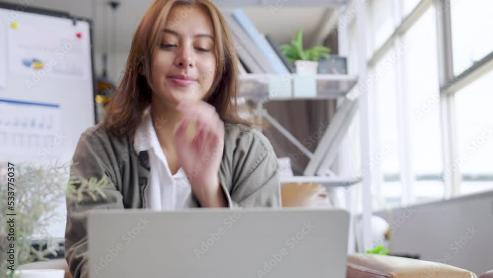 Young Asian woman using laptop on sofa living room at home cozy happy working at home.