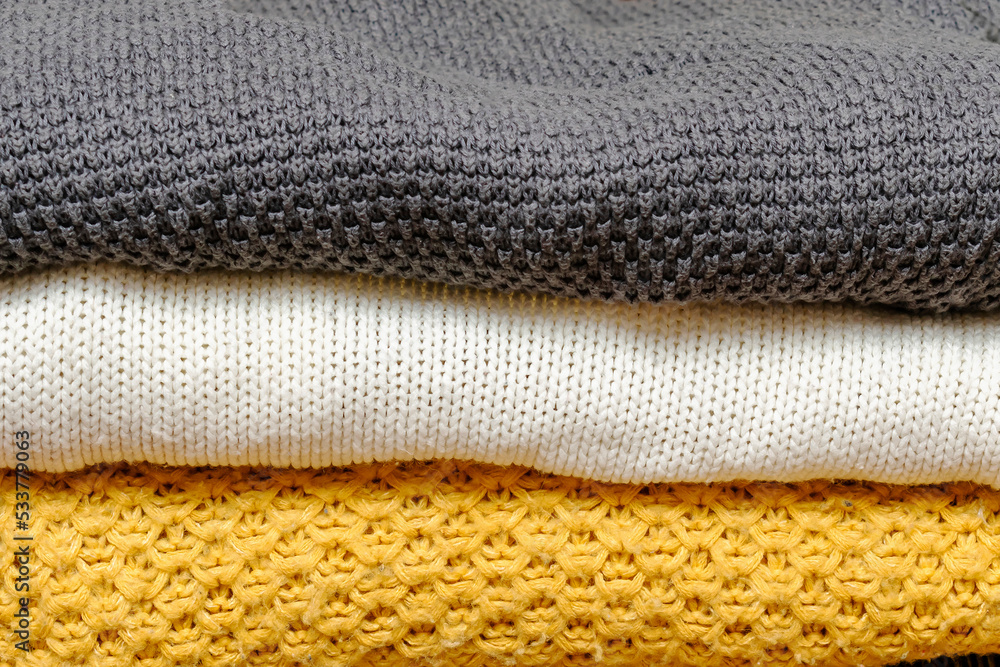 Home wardrobe with winter clothes. Stack of folded cashmere warm woolen knitted sweaters casual womens clothes. Autumn, winter cold season knitwear Home wardrobe with winter clothes. Stack of folded cashmere warm woolen knitted sweaters casual womens clothes. Autumn, winter cold season knitwear