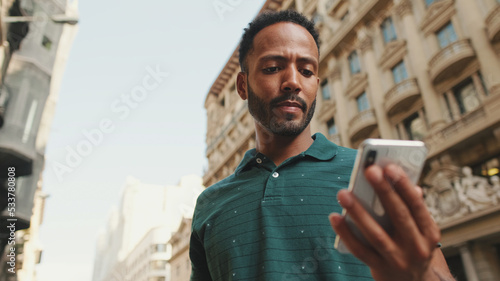 Close-up of young man standing on the street next to the road and using the phone
