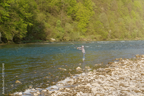 Boy catching fish in a mountain river. Throws the fishing rod.