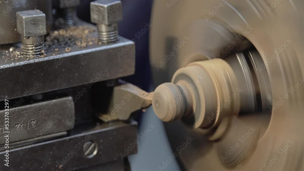 A worker processes a part on a lathe. The part rotates and the cutter removes a layer from it A worker processes a part on a lathe. The part rotates and the cutter removes a layer from it