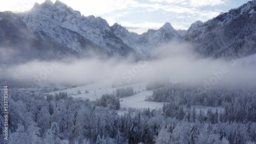 Aerial shot of winter forest and mountains covered in snow, morning fog, frozen forest