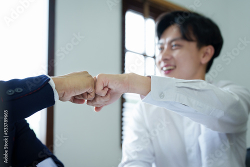 Portrait of two young Asian entrepreneurs congratulating them with smiling faces after successful investment negotiations photo