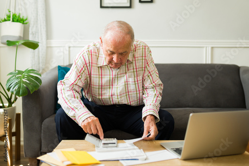 Fototapet Old caucasian man doing his finances and counting his pension money